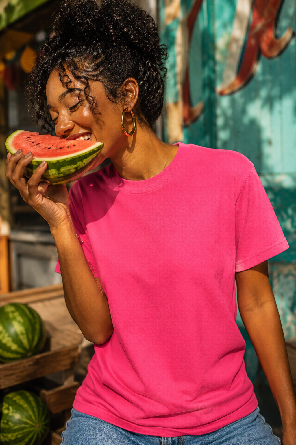 Millennial woman wearing hot pink heavyweight t-shirt while eating a watermelon slice