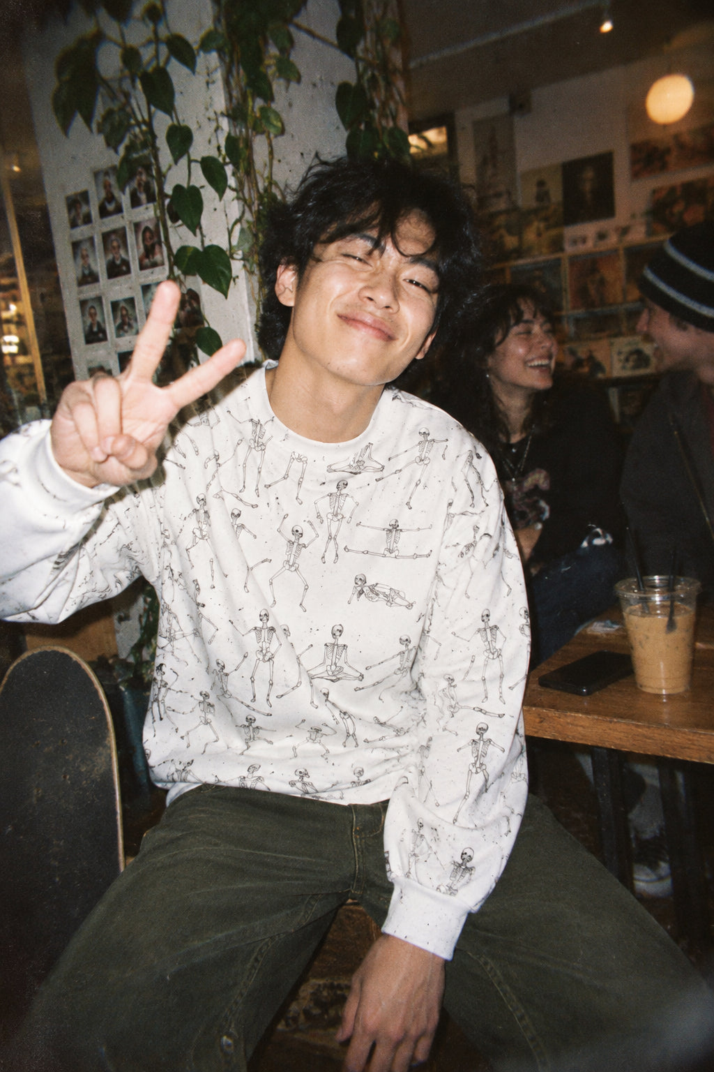 Young man wearing the White Dancing Skeletons Sweatshirt at a casual indoor party