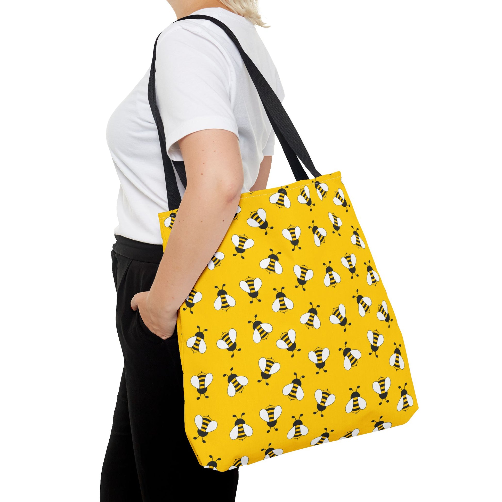Person carrying a yellow bee tote bag with black handles