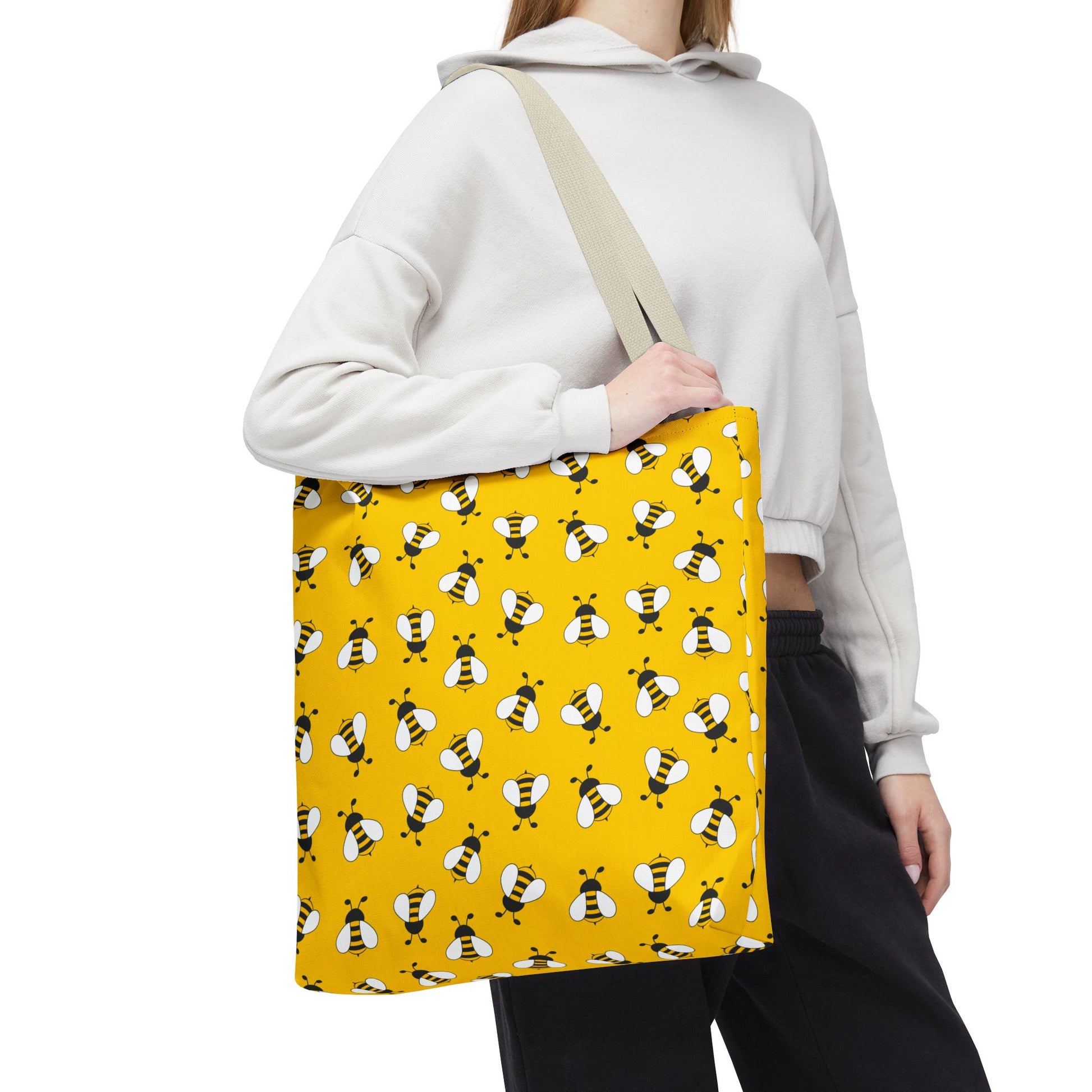 Yellow bee print tote bag with cream handles worn over the shoulder
