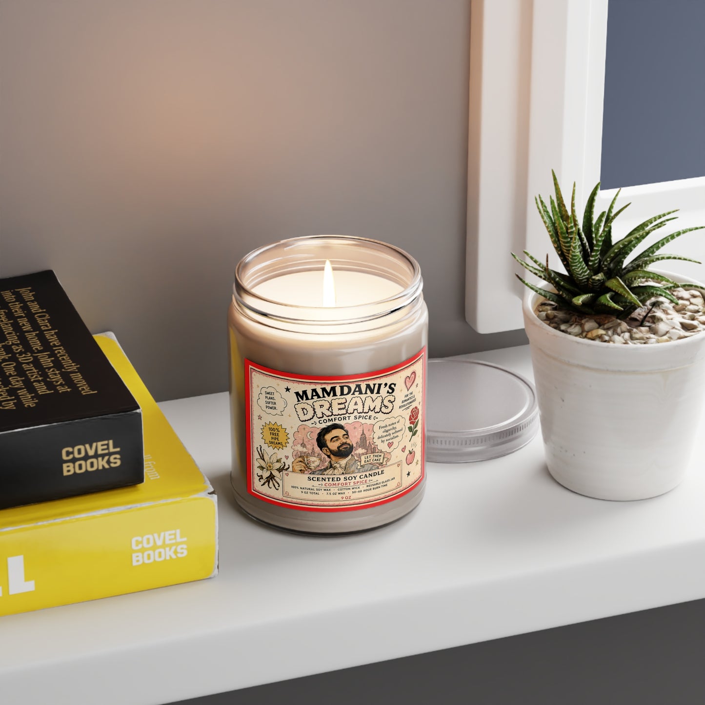 Lit Zohran Mamdani’s Dreams Comfort Spice candle styled beside books and a houseplant